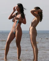 Two girlfriends in bikinis poses in the water outside