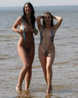 Two girlfriends in bikinis poses in the water outside