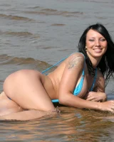 Exciting busty brunette in bikini has fun in the sea flashing her big tits