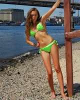 Young baby in green bikini going nude at city beach