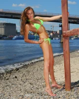 Young baby in green bikini going nude at city beach