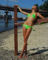 Young baby in green bikini going nude at city beach