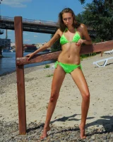 Young baby in green bikini going nude at city beach