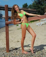 Young baby in green bikini going nude at city beach