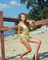 Young baby in green bikini going nude at city beach