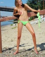 Young baby in green bikini going nude at city beach