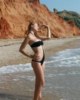 Busty girl in black bikini is swimming nude in the sea