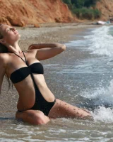 Busty girl in black bikini is swimming nude in the sea