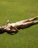 Sexy body brunette in yellow bikini on the grass