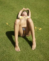 Sexy body brunette in yellow bikini on the grass