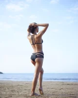 Wonderful chick with tight body is on the beach in sexy bikini and nude on the sand aside at the rocks