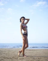 Wonderful chick with tight body is on the beach in sexy bikini and nude on the sand aside at the rocks