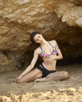 Wonderful chick with tight body is on the beach in sexy bikini and nude on the sand aside at the rocks