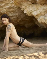 Wonderful chick with tight body is on the beach in sexy bikini and nude on the sand aside at the rocks