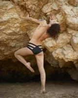 Wonderful chick with tight body is on the beach in sexy bikini and nude on the sand aside at the rocks