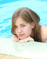 Perfect beautiful teen is by the pool in blue bikini and nude