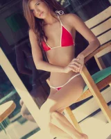 Puffy nipples beauty on the wooden chair in mini bikini